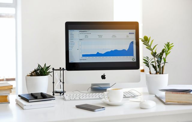 Silver Imac Displaying Line Graph Placed on Desk